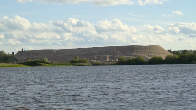 A big mining mountain in the side of the river seen while cruising on the river in Tartu Estonia