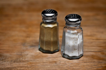 Saltshaker and pepper shaker on a wooden table.