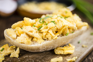 Wooden table with Scrambled Eggs on a bun (selective focus)