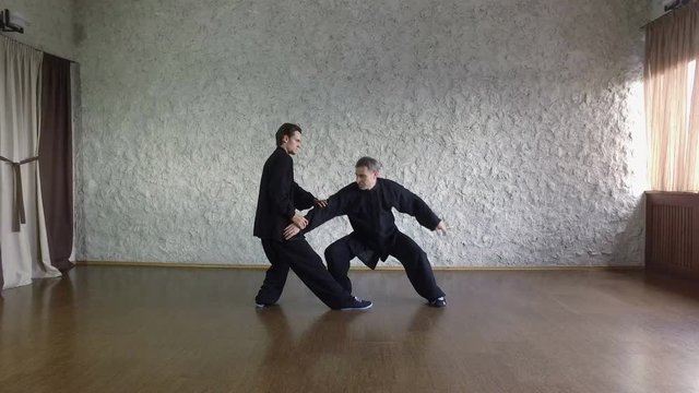 Training in the hall. Two men practicing the elements of tai chi. 4K
