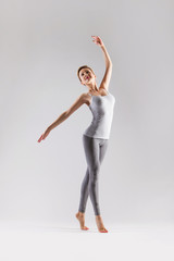Beautiful young woman doing yoga on a gray studio background