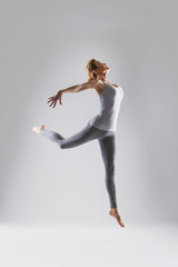 Beautiful young woman doing yoga on a gray studio background