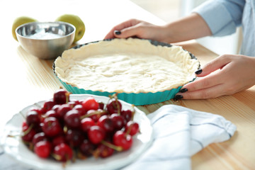 Female hands cooking cherry pie in kitchen