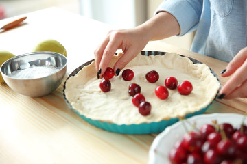 Female hands cooking cherry pie in kitchen