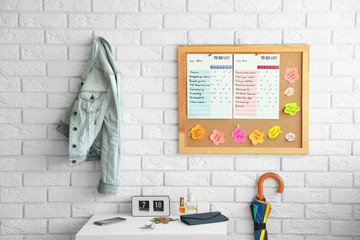 Wooden board with to do list hanging on white brick wall