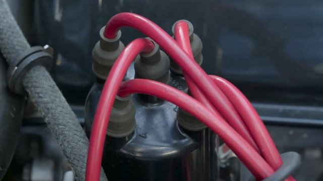 The red wirings from the engine parts of the old car parking outside