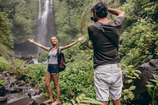 Photographer taking photos of a woman near waterfall