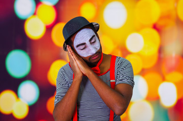 Headshot pantomime man with facial paint posing for camera using hands interacting sleeping, blurry...