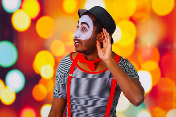 Headshot pantomime man with facial paint posing for camera using hands interacting, blurry lights...