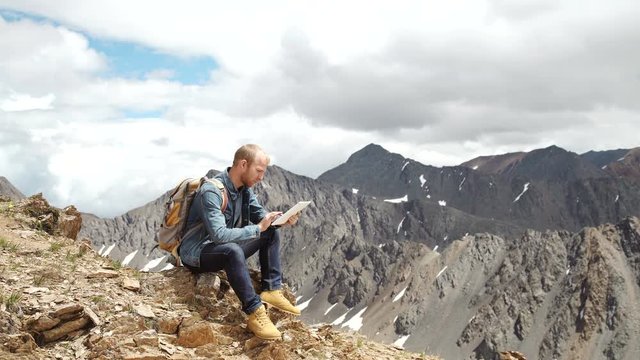 man's hands touching screen of digital tablet on the background of mountains