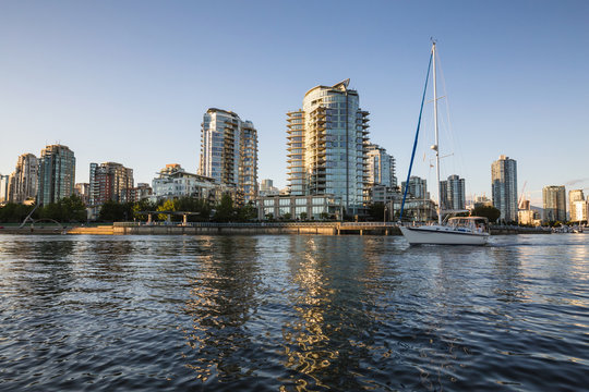 Sail boat in False Creek with the view on the residential buildings in Downtown Vancouver, BC, Canada.