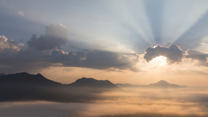 Sun shining behind the clouds on the mountain.