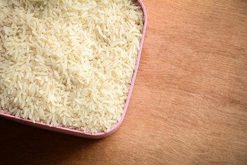 Rice in a white bowl on wooden floor, top view