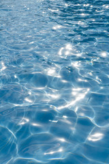 Surface of swimming pool water background with reflective sun li