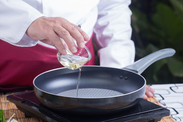 Chef pouring vegetable oil to the pan