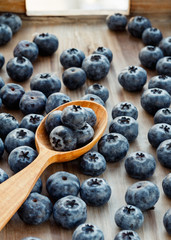 Blueberries and wooden spoon on a wooden background