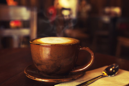 cup of hot coffee on table in cafe with morning light - vintage and dark color tone styles