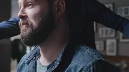 Joyous male client in barbershop looking at his new haircut and giving thanks to his hairstylist