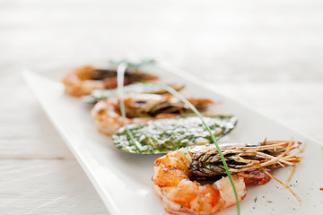 Grilled shrimp and stuffed mussel on white, close-up. Prepared mediterranean meal of fresh seafood