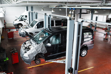 Industrial car lifting at modern repair shop. Minibuses service maintenance at professional workshop.