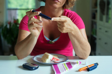 Close up of a woman using lancelet on finger to take sample of blood sugar.