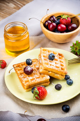 Waffles with berries on wooden background