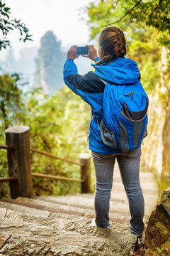 Young female tourist with blue backpack taking photo