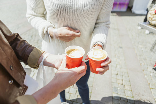 Friends holding coffee cups while standing on street