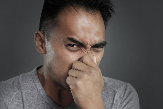 Portrait Of A Man Pinching His Nose On A Gray Background