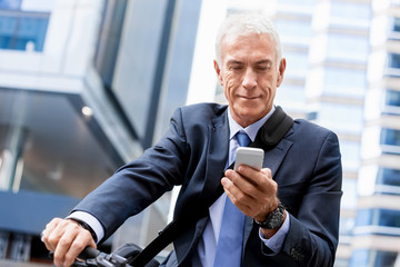 Successful businessman on bicycle with mobile phone