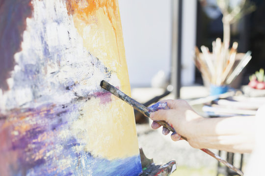 Cropped image of senior female artist painting at easel outdoors