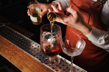 Barman pouring hard spirit into glass in detail