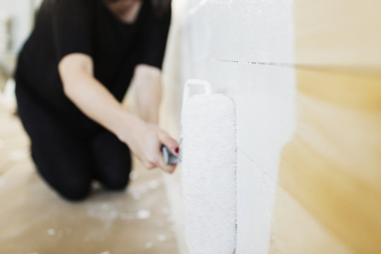 Woman painting wall with paint roller