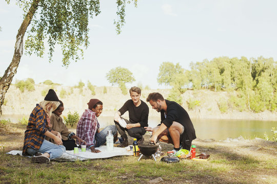 Multi-ethnic friends enjoying picnic at lakeshore