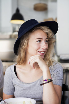 Smiling woman wearing black hat sitting in restaurant