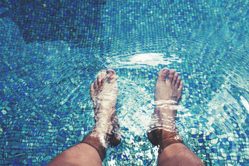 Male feet with skin tan, dipping in swimming pool