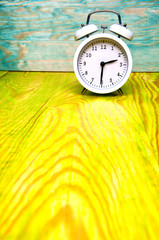 White alarm clock isolated on colorful wooden background