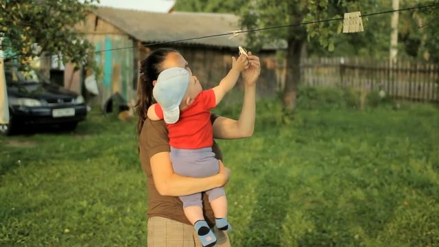 Mom plays with the baby in a beautiful garden with clothespins. Adorable baby less than a year