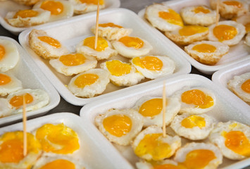 Fried quail eggs on the market close up