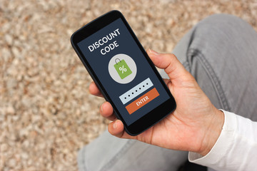 Hand holding smart phone with discount code concept on screen. All screen content is designed by me.