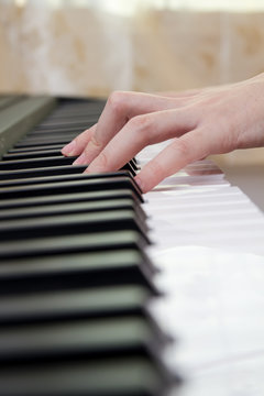 Girl's hands on the keyboard of the piano