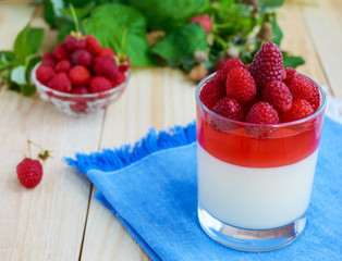 Summer dessert with cream and raspberry jelly, decorate with fresh berries in a transparent glass.