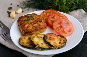 Fried cutlet, tomato and zucchini on a white plate