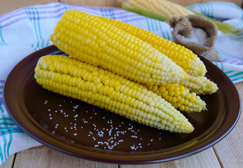Boiled cobs of sweet corn on a clay plate