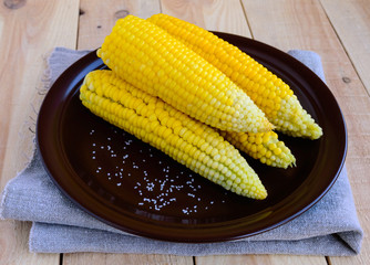 Boiled cobs of sweet corn on a clay plate