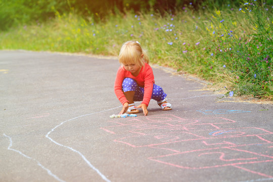 little girl drawing hopscotch on playground