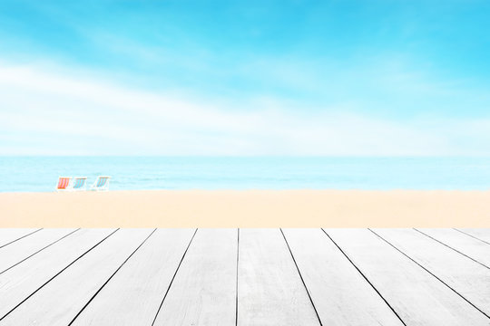 Wood floor with white blue surfing wave background. Blue cool water and sky bright with ray light. Nature wallpaper blur of sea daytime. Focus to wooden in the foreground. Timber pattern texture stage