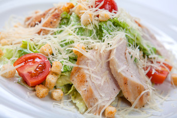 Caesar salad with chicken on white plate.