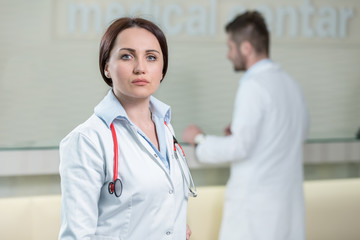 Portrait of woman doctor at hospital corridor, looking at camera.