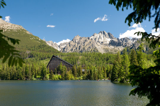 Strbske pleso in High tatras in summer witg trees in the front. High tatras mountains. Vysoke tatry. Slovakia. Nature of Slovakia. Hotel Patria. Lake. Mountains. Forest.